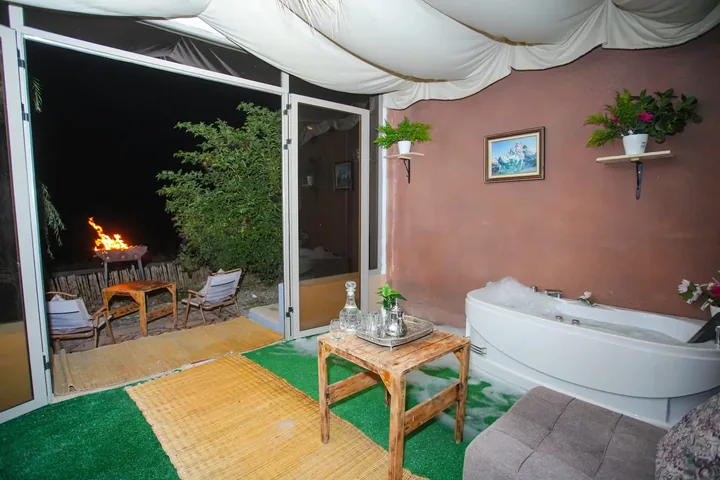 Le jacuzzi, porte ouverte sur la terrasse et le feu allumé dehors.